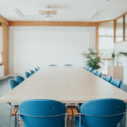 Frontalansicht: lange Tischtafel mit blauen Konferenzstühlen.