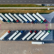 Ein Parkplatz von oben. In den Parkbuchten stehen viele LKWS.