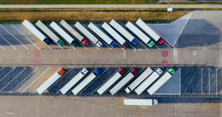 Ein Parkplatz von oben. In den Parkbuchten stehen viele LKWS.